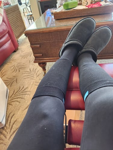 Customer relaxing with their legs propped up, wearing black Performance Eucalyptus Compression Socks.