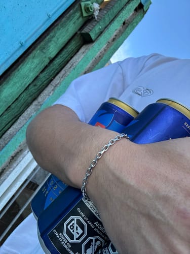 Un cliente mostrando la Pulsera Geneva plateada de eslabones en su muñeca en un entorno casual.