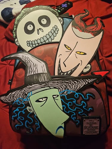 Reviewer's Loungefly backpack with colorful Lock, Shock, and Barrel appliques resting on a red surface.