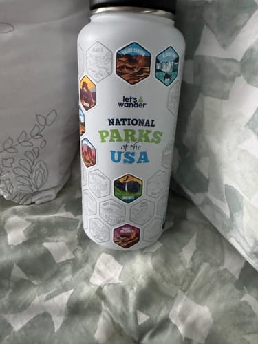Customer's white National Parks water bottle with several colorful hexagonal stickers applied.
