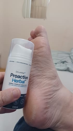 Vásárló a Proactive Herbal+ krémet tartja a kezében, a háttérben egy talp látható.