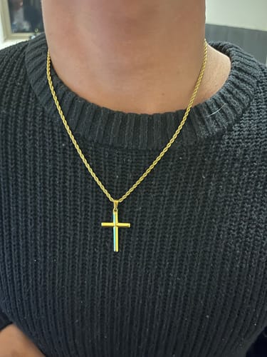Un cliente lleva puesto el colgante Crucifix Pendant Oro sobre un suéter negro.