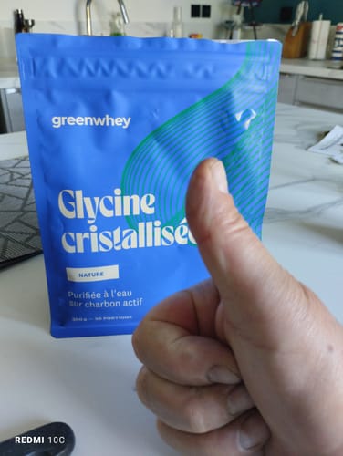 Client faisant un pouce levé devant le sachet bleu de Glycine cristallisée posé sur un comptoir.
