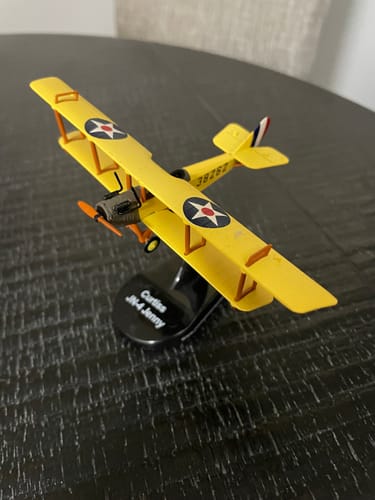 Customer's yellow JN-4 Jenny US Air Mail Service model biplane shown on its black display stand on a table.