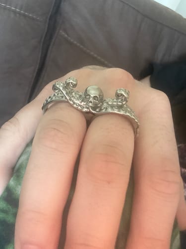 A customer's hand wearing the detailed DOUBLE FINGER OCTOSKULL RING on their index and middle fingers.