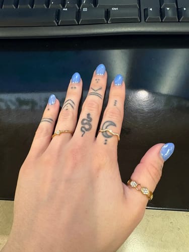 Reviewer's hand with blue nails and tattoos, wearing the Gold & Crystal Honeycomb Ring on their thumb.
