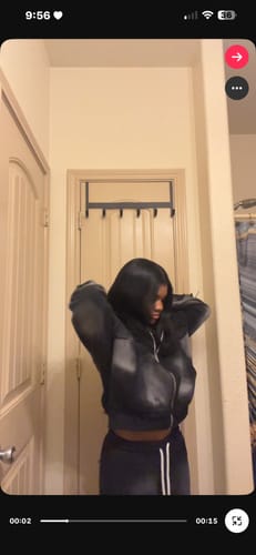 Reviewer wearing the dark, puffy SEEK VISIONZ SET and adjusting the jacket in a hallway.