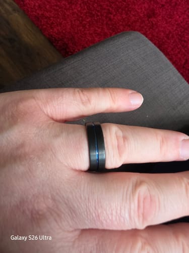 Customer wearing the black Stratus ring with a vivid blue groove on their finger against a dark background.
