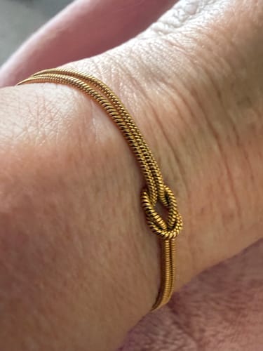 Customer's close-up of the gold Forever Knot Bracelet worn on their wrist.