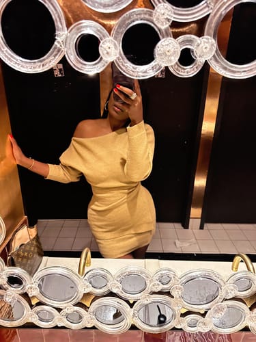 Reviewer taking a mirror selfie wearing the gold Knit Off-Shoulder Asymmetric Top in size medium.