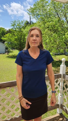 Reviewer showing the fit of the Mia V Neck tee in Estate Blue while standing on an outdoor porch.