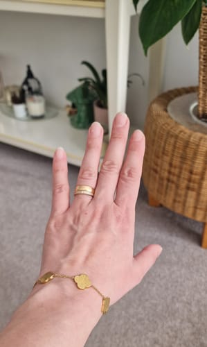 Customer showing the gold Sabr, Shukr, Tawakkul Bracelet on their wrist in a home setting.
