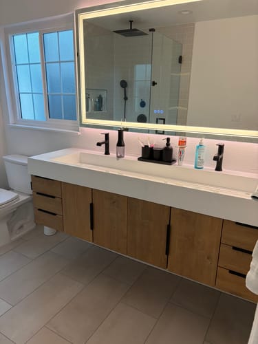 Customer's Breton Floating Vanity with a wood finish and double trough sink, installed in a bright, modern bathroom.