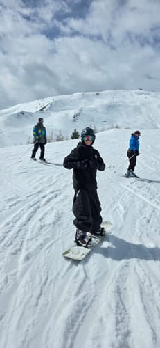 Reviewer on a snowboard wearing the black baggy snow pants on a snowy mountain.