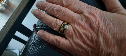 Customer's hand wearing the black Titanfall ring with a gold inlay, stacked with a diamond engagement ring.