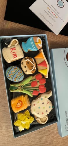 Reviewer's open Easter Breakfast Deluxe Biscuit Box, showing colorful biscuits shaped like flowers, a teapot, and an egg.
