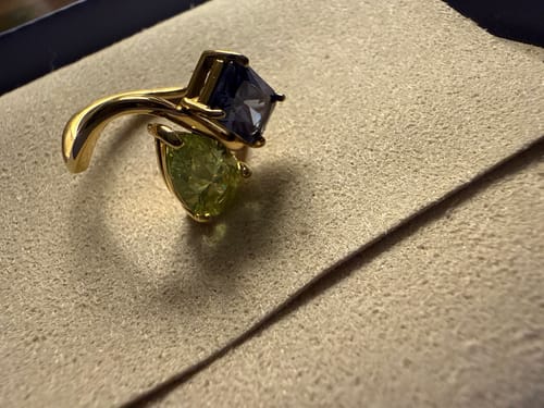 Customer's Navae Birthstone Ring with a green pear-cut stone and a blue radiant-cut stone in a box.