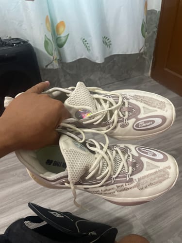 Customer holding up a pair of white XTEP Lin Storm 2 Basketball Shoes, showing the side design and mesh tongue.