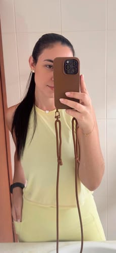 Cliente tirando uma selfie no espelho para mostrar a case Nora Mocha Mousse com sua alça fina.