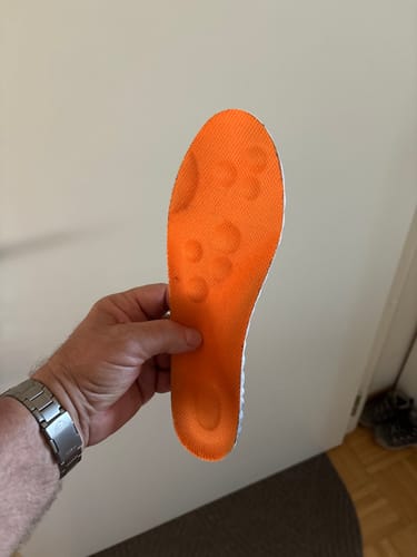 Vásárló egy narancssárga AIRFIT ULTRA talpbetétet tart, amelyen látszanak a használat nyomai.