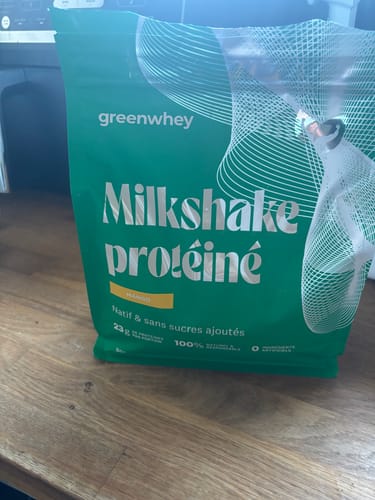 Avis d'un client : sachet de Milkshake protéiné saveur mangue posé sur une table en bois.