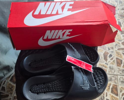 Customer's black Nike Victori One Shower Slides with tags attached, shown next to the red Nike box.