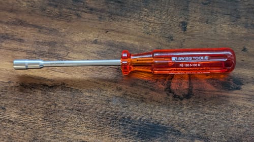 Customer's PB Swiss Tools bit holder, with its classic red handle and long metal shaft, on a wooden table.