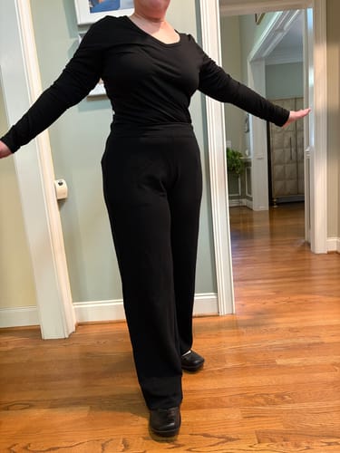 Customer modeling the relaxed, wide-leg fit of the black Brynn Pants in a home.