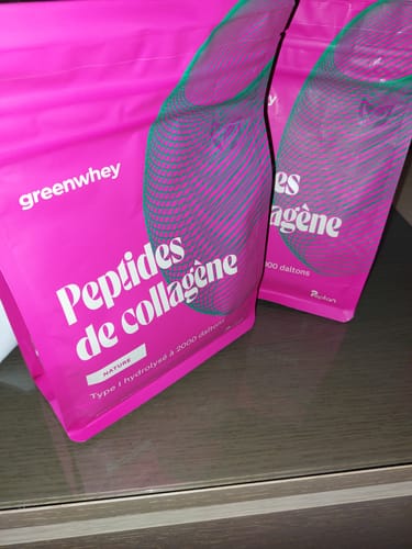 Photo d'un client montrant deux sachets roses de Peptides de Collagène, saveur Nature, posés sur une table.