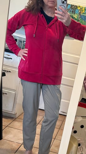 Reviewer shows a front view of the poppy Ryann Hoodie, fully zipped up.