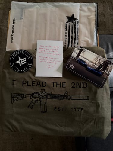Customer's olive green shirt with 'I PLEAD THE 2ND' and a rifle graphic laid out with a patch and thank-you note.