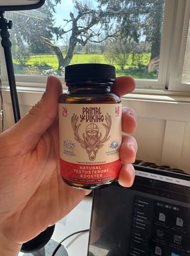 Customer holding a bottle of Primal Reindeer Testosterone Support in front of a window.