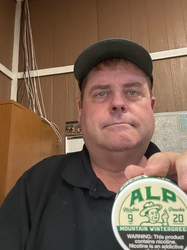 Reviewer holding up a can of Mountain Wintergreen Nicotine Pouches for the camera.