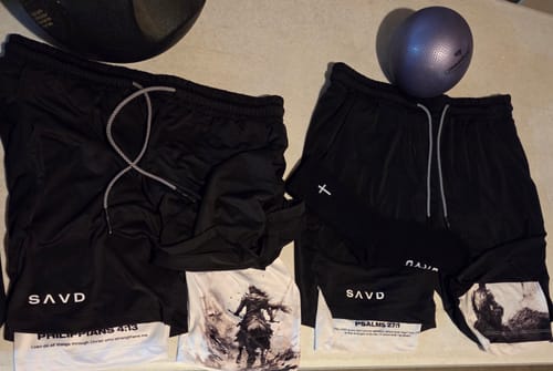 Reviewer's two pairs of black athletic shorts with scripture verses on the white inner compression lining.