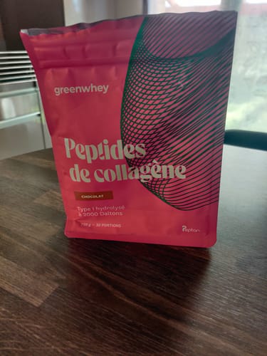 Sachet rose des Peptides de Collagène du client, saveur chocolat, posé sur une table en bois.