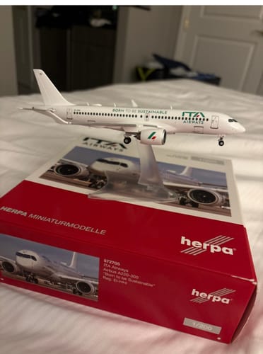 Customer's HERPA ITA A220-300 model airplane displayed on its stand on top of the red product box.