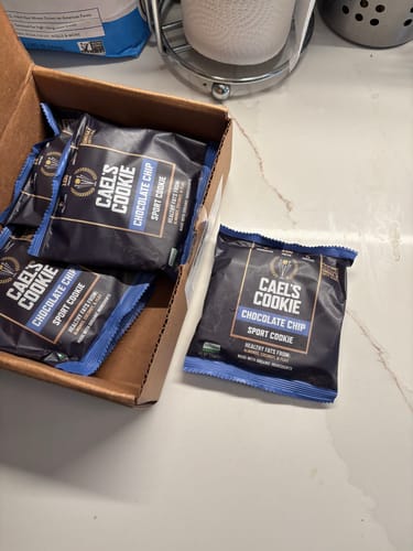 Reviewer's open box of Cael’s Cookie Chocolate Chip packages on a kitchen counter.