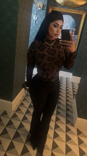Reviewer taking a mirror selfie wearing the long-sleeved Naked Print Bodysuit with black pants.