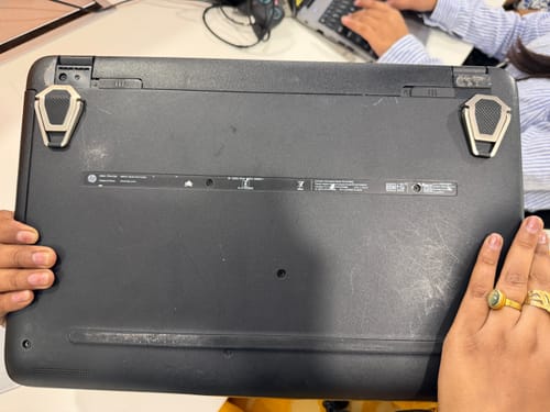 Reviewer showing two folded Casence AirStands attached to the underside of a black laptop.