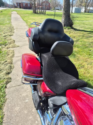 Customer's black mesh Wind Rider Seat Cover installed on a red motorcycle parked on a sidewalk.