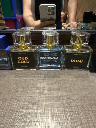 Customer's three Khushboo-e-Ramzan perfumes, Oud Gold, Oud Nirvana, and Rumi, lined up on a wooden surface.