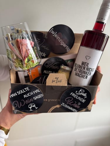 Ein Kunde hält eine Geschenkbox mit dem gravierten Leonardo Weinglas und anderen passenden Geschenkartikeln.
