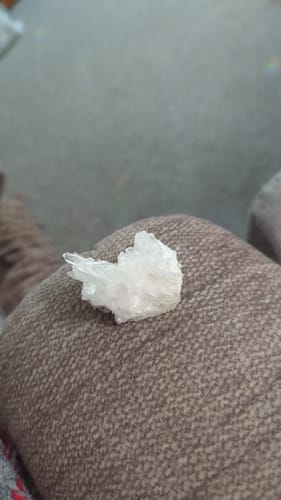 Customer's small clear quartz crystal cluster resting on a brown textured surface.