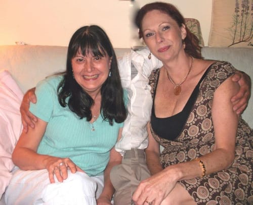 Reviewer in a blue shirt and her friend smiling together on a couch after trying Gelato.