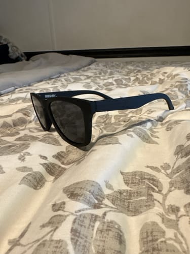 Customer's 80Eighty Polarized Shady Sunglasses with a matte black frame resting on a bedspread.