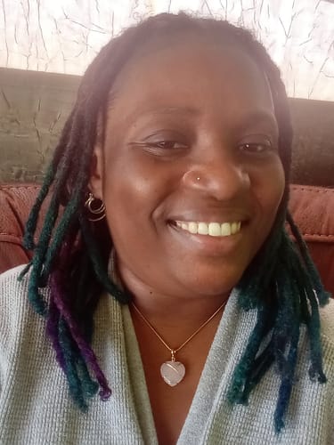 Reviewer smiling while wearing a lovely rose quartz heart pendant necklace.