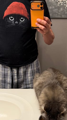 Reviewer taking a mirror selfie wearing the black Statement Made t-shirt with a cat graphic.