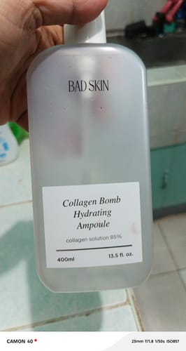 Customer holding the large, translucent bottle of Bad Skin Collagen Bomb Hydrating Ampoule.