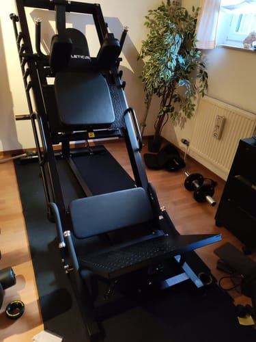 Rezensent zeigt die aufgebaute schwarze Beinpresse Hackenschmidt Combo in einem Heimgym.