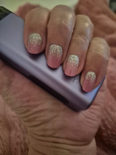 Hand einer Kundin, die die pinken UV-Gelfolien 'Glitter Dizzle' mit einem funkelnden Silber-Ombré trägt.